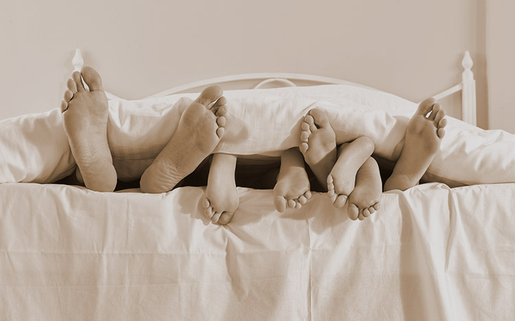 Family feet under bed cover
